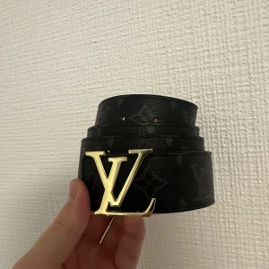 Svart bälte - Svart stilrent bälte med guldig badge i storlek 110