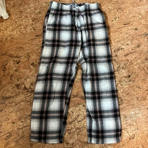 Rutiga byxor från 157 med snörning - Rutiga byxor från 157 i svart, vitt och beige med elastisk midja och snörning. Lätta och sköna med avslappnad passform, perfekta för chill dagar. Mjukt bomullsmaterial och raka ben ger en casual vibe.