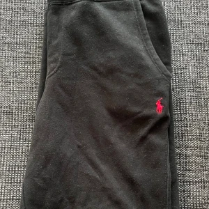 Svarta mjukisbyxor Polo Ralph Lauren - Svarta mjukisbyxor från Polo Ralph Lauren med klassisk röd broderad logga på höften. Byxorna har resår i midjan och är tillverkade i mjukt bomullsmaterial. Perfekta för en chill och avslappnad stil.