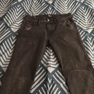 Svarta Replay Anbass jeans, W29 L32 - Snygga svarta Replay Anbass jeans med klassisk femficksdesign och diskreta slitningar. Modellen har smal passform och raka ben, tillverkade i stretchigt jeansmaterial för extra komfort. Perfekta för dig som gillar stilrena och moderna jeans.