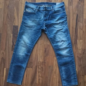 Diesel Tepphar slim jeans blå W34 - Snygga blå Diesel Tepphar jeans i slim-carrot fit med stretch. Jeansen har klassisk femficksdesign, slitningar och snygg tvätt för en cool look. Perfekta för dig som gillar en smalare passform och vill ha ett par bekväma jeans med modern stil.