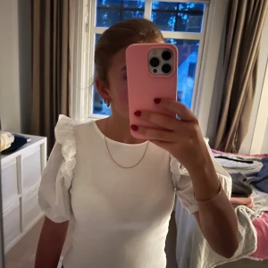 Vit puffärm blus från Zara - Supersöt vit blus från Zara med puffiga korta ärmar och volangdetaljer på axlarna. Toppen har fyrkantig ringning i ryggen och är lätt croppad. Ganska kort i modellen. Perfekt att styla med jeans eller kjol för en trendig look. 🤍🤍🤍