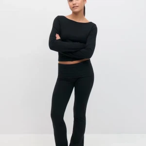 Svarta bootcut yogapants - Svarta yogapants med bootcut-snitt och hög midja. Byxorna är i ett stretchigt och mjukt material som sitter skönt på kroppen. Perfekta för en chill och avslappnad stil. Passformen är loose och de har en enkel, stilren look utan detaljer.