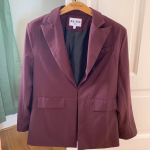 Vinröd blazer/kavaj nakd  - Vinröd kavaj. Den är tunn så passar bra på sommaren. Bra skick men behöver strykas. De två ljusa prickarna på första bilden är inte fläckar det är dammpartikel som yrde😐
