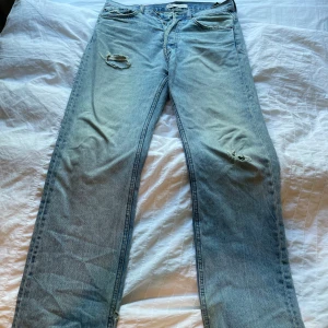 Ljusblå raka jeans från Zara - Ljusblå jeans från Zara med raka ben och slitna detaljer på låret och knät. Klassisk femficksmodell i denim med normal passform. Perfekta för en avslappnad och trendig look.