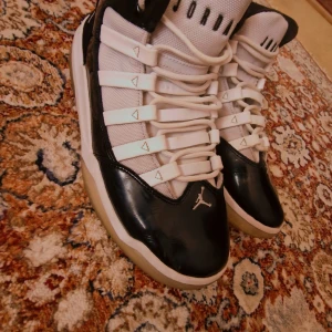 Nike Air Jordan 11 Retro svart/vit - Säljer ett par Nike Air Jordan 11 Retro i svart och vitt. Skorna har en hög siluett, snörning och ikonisk Jumpman-logga på sidan. Ovandelen är i blankt skinn och mesh, med vit mellansula och genomskinlig yttersula. Perfekta för dig som gillar klassiska sneakers med streetkänsla.