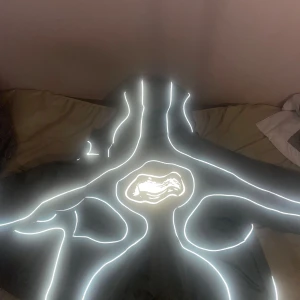 Nike x Corteiz Vindjacka med reflex - Nike x Corteiz vindjacka i grått med reflekterande detaljer och unikt mönster på ryggen. Insidan har camouflage-tryck. Jackan har huva, dragkedja och justerbar nederkant. Perfekt för dig som vill sticka ut med både stil och funktion.