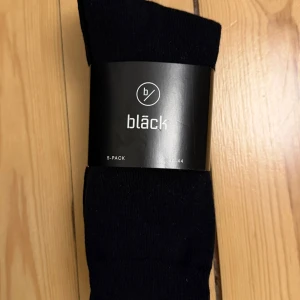 Svarta strumpor 5-pack från Bläck - Säljer ett 5-pack klassiska svarta strumpor från Bläck. Strumporna är i en skön blandning av 75% bomull, 22% polyamid och 3% elastan, vilket gör dem både mjuka och stretchiga. Perfekta för dig som vill ha stilrena och bekväma strumpor till vardags. Storlek 40-44.