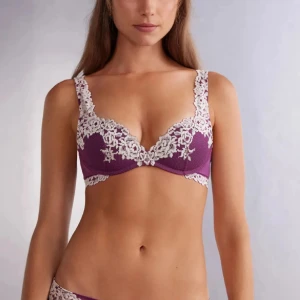 Lila intimissimi BH - Superfin lila push up bh från intimissimi med vita blommiga spetsdetaljer längs kanterna och axelbanden. Bh:n har en klassisk form med bygel och ger ett snyggt lyft. Perfekt för dig som gillar romantiska och feminina underkläder.