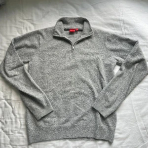 Grå stickad half zip-tröja RYVLS - Mysig grå stickad tröja från RYVLS med half zip-dragkedja och hög krage. Perfekt för lager-på-lager under kyliga dagar. Långärmad och i klassisk, enkel design som funkar till det mesta.