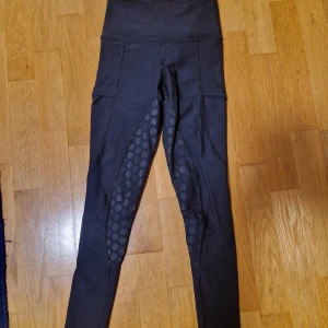 Svarta ridleggings Maya Delorez 2XS. Perfekt skick - Svarta ridleggings från Maya Delorez med hög midja och smarta fickor på sidorna. Snygga silikonmönster på insidan av benen för extra grepp i sadeln. Stretchigt och bekvämt material. Mycket bra skick. Endast handtvättade.