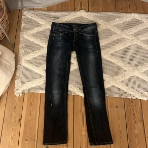 Mörkblå jeans från ONLY W25 L34 - Snygga mörkblå jeans från ONLY med slitna detaljer och kontrastsömmar. Klassisk femficksmodell med raka ben och låg midja. Jeansen har coola nitar på bakfickan och en schysst tvättad look. Perfekta för dig som gillar en avslappnad men trendig stil. Storlek 25/34 men skulle säga att de är väldigt korta i längden.
