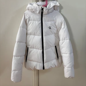Vit dunjacka från Calvin Klein - Säljer en fin vit jacka från Nike som knappt är använd och därav är i ett mycket bra skick. Storleken är i 14 år men skulle säga att den passar XS/S