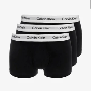 Calvin Klein svarta trunks 3-pack - Ett helt oanvänt 3-pack svarta kalsonger från Calvin Klein med vit resår och logga runt midjan. Perfekta för dig som gillar klassisk och stilren design.