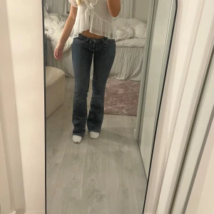 Bootcut jeans i mörkblå denim - Säljer ett par snygga bootcut jeans i mörkblå denim med klassiska fickor och kontrastsömmar. Jeansen har låg midja och en lätt utsvängd passform nertill. Perfekta för dig som gillar en tidlös och cool look.