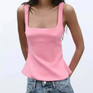 Rosa linnetopp med rosett i ryggen - Säljer en ljusrosa linnetopp med fyrkantig halsringning och breda axelband. Toppen har en snygg öppen rygg med stor rosett som detalj. Materialet är slätt och känns mjukt mot huden. Perfekt för dig som vill ha en söt och trendig look.