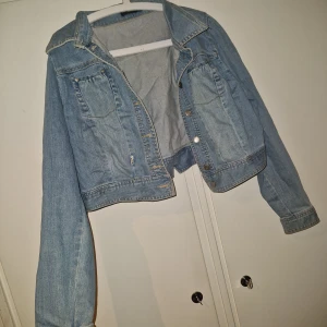 Jeansjacka  - Snygg ljusblå jeansjacka från Plus Collection med klassisk krage, två bröstfickor med knappar och dekorativ sömnad. Jackan har långa ärmar och en croppad passform som ger en trendig look. Perfekt för dig som gillar denim och vill ha en stilren jacka i garderoben.