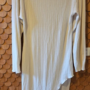 Vit ribbad långärmad klänning H&M - Vit ribbad klänning från H&M i storlek L. Klänningen har lång ärm, rak passform och är tillverkad i ett mjukt, stretchigt material. Fin sne slits. Inte jätte genomskinlig men man kan se ytte pytte igenom