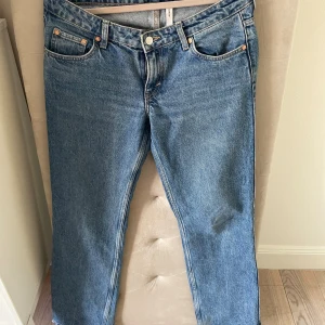 Arrow low jeans från Weekday - Klassiska blå arrow low jeans med rak passform och fem fickor. Jeansen har normal midja, knappgylf och är tillverkade i slitstarkt denim. Perfekta för en avslappnad och tidlös look. Skulle säga att de är storlek 36💞lite slitna längst ner