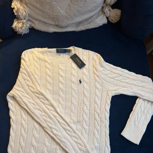 Kabelstickad tröja Polo Ralph Lauren - Kabelstickad ljusbeige tröja från Ralph Lauren. Tröjan är helt ny och aldrig använd förutom när fotot på första bilden skulle tas till annonsen. Storleken är S och egentligen för män men skulle säga att den passar kvinnor i storlek S/M också. Jag är själv S och kan bära den. Tröjan är äkta men köpt i usa (i en Ralph Lauren butik) nypris 2400kr :)