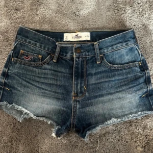 Blåa lågmidjade jeansshorts från Hollister - Snygga blå lågmidjade jeansshorts från Hollister. Jag säljer shortsen för att dom var för småa när jag köpte dem, så dom har inga skador eller fläckar!🤗