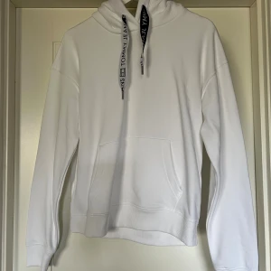 Vit hoodie  - Vit hoodie från Tommy Jeans med svartvita snören. Aldrig använd. 