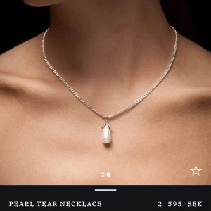 Silverhalsband med droppformad pärla - Stilrent halsband i silver med en droppformad vit pärla som hänge. Kedjan är klassiskt länkad och pärlan har en elegant infattning upptill. Perfekt för dig som gillar minimalistiska och tidlösa smycken. Pärlan är precis ny bytt och helt ny!