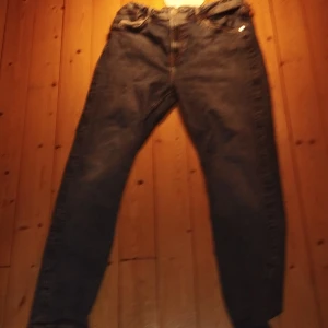 Blå relaxed jeans från H&M, stl 170 - Säljer ett par blå relaxed fit jeans från H&M med justerbar midja och klassiska gula sömmar. Jeansen har dragkedja och knapp framtill, raka ben och är tillverkade i bomull. Perfekta för en chill och avslappnad stil.