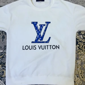 Vit Louis Vuitton sweatshirt med blå logga - Den kända Louis Vuitton tröjan för fem gånger mindre pengar. Detta är ett måste i din garderob för både stil och komfort. Tröjan har fantastisk kvalitet för sitt låga pris, och jag köpte den från en privat agent för nästan dubbla priset. Först till kvarn!! 🔥🫡  Priset kan diskuteras, men endast med seriösa köpare.