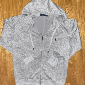 Polo Ralph Lauren tröja-dragkedja  - En tjocktröja med huva och dragkedja från märket Polo Ralph Lauren. Tröjan är i Storlek L men sitter som S 