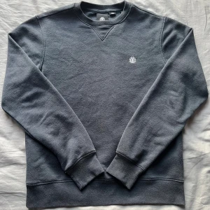 Mörkgrå sweatshirt från Element XS - Mörkgrå sweatshirt från Element i storlek XS. Tröjan har rund halsringning, ribbade muddar och ett litet broderat Element-logo på bröstet. Perfekt basic med lång ärm och mjukt material som passar till allt.  Längd: 61cm Bredd: 47cm Axelbredd: 42cm. Skriv privat om pris eller frågor!💯👍 