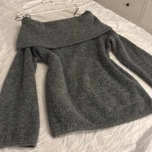 offshoulder stickad tröja H&M - Mysig mörkgrå stickad tröja från H&M med bred offshoulder-ringning. Tröjan har lång ärm och en loose passform som ger en chill vibe. Perfekt för kyliga dagar när du vill vara både bekväm och snygg. I mycket bra skick, skriv om ni har frågor💕💕