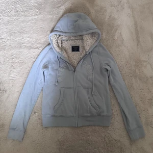 Ljusblå zip up hoodie från Abercrombie - Mysig ljusblå hoodie från Abercrombie & Fitch med fluffigt foder! 
