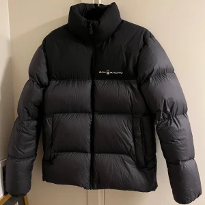 Svart pufferjacka från Sail Racing - Varm vinterjacka. Finns små "osynliga" fläckar. I övrigt nyskick. Luva i kragen man kan ta i och ur. Det är storlek 170. Så passar S🌸