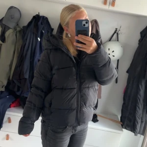 Svart pufferjacka med huva från Everest  - Säljer en svart pufferjacka från Everest med stor huva och dragkedja framtill. Jackan är vadderad och har en klassisk, lite oversized passform som är perfekt för kalla dagar. Jackan är i Storlek 34(jag brukar ha storlek S på tröjor). Säljer eftersom den är lite för puffig för min smak. Priset går att diskutera. Liten skråma på högra armbåge, en liten defekt man verkligen inte lägger märke till. 