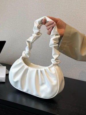 Vit axelväska - Säljer en superfin vit axelväska med scrunchie-inspirerat handtag. Väskan har en mjuk, rundad form och är gjord i slätt syntetmaterial. Perfekt storlek för det viktigaste och ger en trendig touch till din outfit.