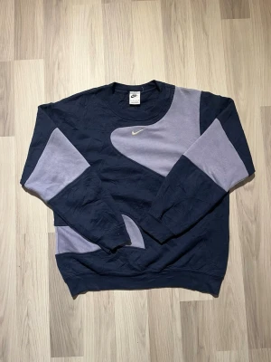 Unik Vintage Nike Sweatshirt  - Säljer en riktigt snygg sweatshirt från Nike i marinblått och ljusblå med broderad logga på bröstet. Tröjan har coola färgblock, rund hals och långa ärmar. Tillverkad i mjuk bomull, perfekt för chill dagar eller streetwear. Står att det är XS men är stor i storleken så sitter mer som S/M. Skickas snabbt och välpackat!