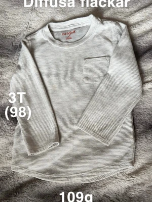 Grå ribbad långärmad t-shirt Cat & Jack - Säljer en grå långärmad t-shirt från Cat & Jack i storlek 3T (98). Tröjan har ett ribbat mönster och en liten bröstficka som detalj. Perfekt för dig som gillar enkel och stilren design.🌸 Diffusa fläckar. Storlek 3T vilket motsvarar 98