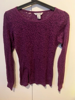 Lila leopardmönstrad topp Derek Heart - Säljer en tunn, långärmad topp från Derek Heart i lila med leopardmönster. Modellen är figurnära och materialet är en mix av bomull och polyester som känns lätt och stretchig. Perfekt att styla med jeans eller kjol för en cool look.