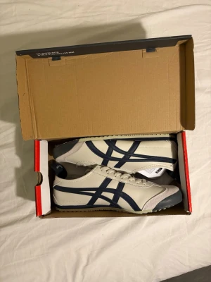 Onitsuka Tiger Skor - Säljer nu ett par helt nya vita och blåa onitsuka tiger skor! Allt följer med, inga defekter! Priset går att diskutera vid snabb affär!