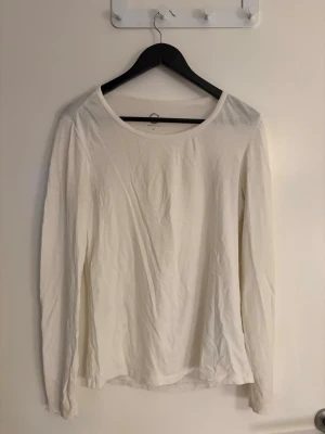 Dam Vit långärmad topp  - En enkel och stilren vit långärmad topp i i storlek M. Modellen har rund halsringning och en rak passform som funkar till det mesta. Perfekt basplagg att ha i garderoben och lätt att matcha med olika stilar.