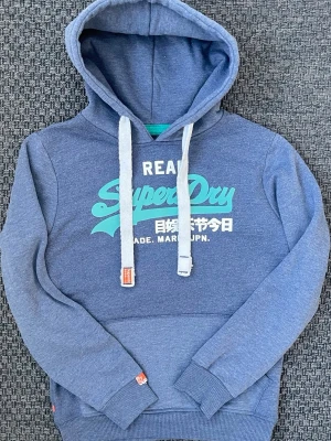 Vintage 2000s Superdry hoodie JPN (Nyskick) - Säljer nu denna sjukt snygga vintage 2000s Superdry hoodie! Passar perfekt till allt 😊Säljs ej längre i butik och är ur en limiterad upplaga. Hoodien är därav mycket eftertraktad 🙌 Storleken på etiketten är L men den passar S 🤩 Helt perfekt passform och endast använd 1 gång! Skriv vid funderingar 📲