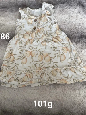 Blommig kortklänning från Newbie - Supersöt kortklänning från Newbie med blommigt mönster i ljusa toner och volangdetaljer. Klänningen är ärmlös och har knappar framtill. Perfekt för varma dagar och ger en somrig känsla.🌸 Fint använt skick. Storlek 86 