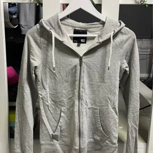 Grå tjocktröja med dragkedja - Kan sänka pris vid snabb affär. Grå tjocktröja med dragkedja från Lager 157. Väl använd men inga skador eller fläckar. Gillar man tajtare tröjor passar denna även som storlek S och blir då slimfit. Kolla gärna in mina andra annonser🥰