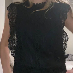 Svart spetsblus med volangdetaljer - Säljer en svart blus med vackra spetsdetaljer och volangkantade ärmhål. Från Only🥰