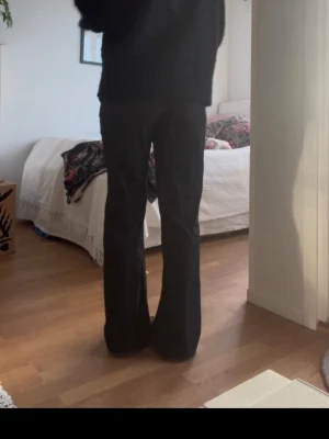 Svarta bootcut kostymbyxor - Säljer ett par svarta kostymbyxor med bootcut passform och låg midja. Byxorna har raka ben som blir vidare nedtill och är sydda i ett mjukt, välsittande tyg. Perfekta om du gillar en clean och stilren look.