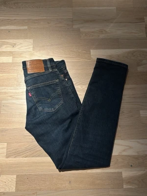 Levi's 511 mörkblå  - Säljer ett par riktigt fräscha Levi's 511 jeans i mörkblå färg. Jeansen har den ikoniska läderpatchen bak i midjan och röda Levi's-taggen på bakfickan.  Strl w28/L32