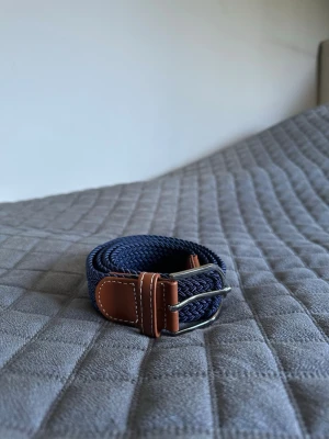 Mörkblått flätat bälte - Tja det är helt nytt från Bältgallerian. Det är 105cm långt och 3,5cm brett. Det är i ett elastiskt material så passar större storlekar också. Om du inte gillar den här färgen så finns det många flera att välja mellan. Vid köp av bundle så blir kostnaden billigare.