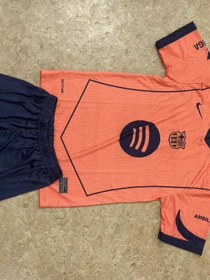 Ingen skor på bilderna - Bilderna visar ett fotbollsställ med tröja och shorts, men inga skor finns med. Kan därför inte ge någon skobeskrivning eller matchande taxonomier.