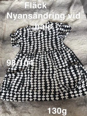 Svartvit prickig klänning  - Säljer en svartvit klänning med coolt prickigt mönster och två stora fickor fram. Klänningen har korta ärmar, perfekt för lek och vardag. Superskön passform och snygg design!🌸 Fläck. Nyansändring vid halsen. Storlek 98/104